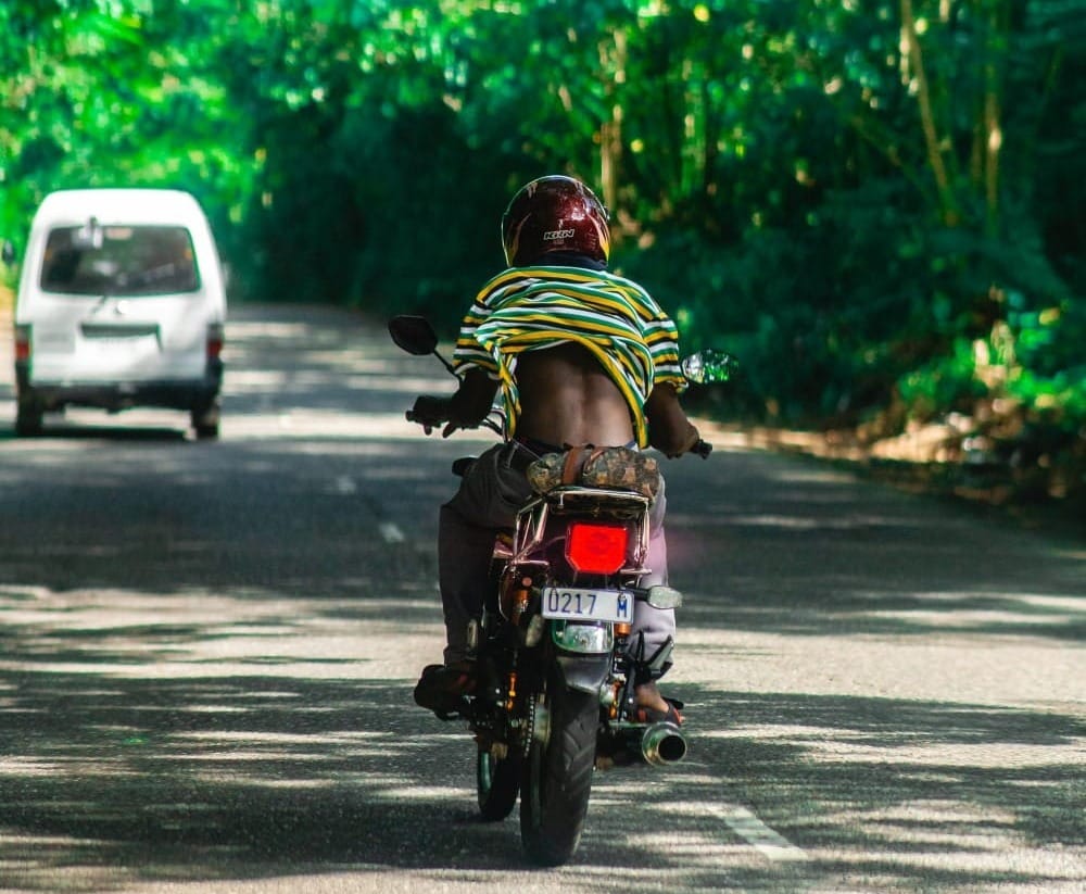 man in green and yellow shirt riding motorcycle on road during daytime